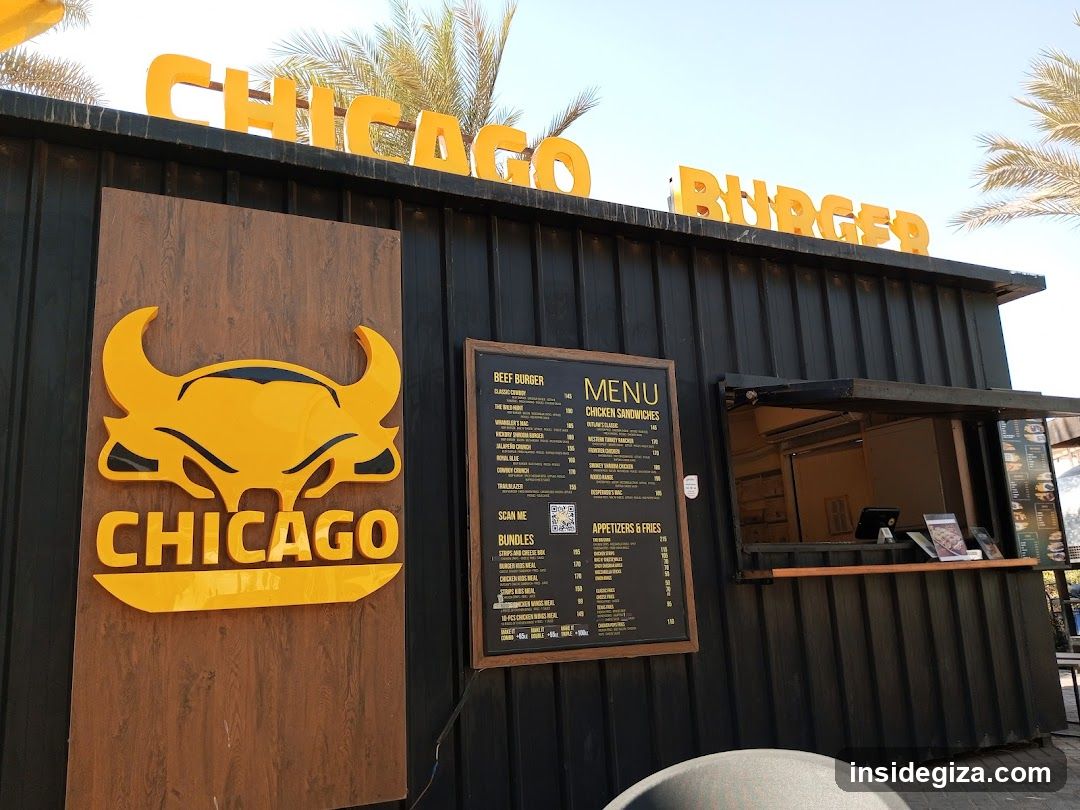 A black corrugated metal shop front with yellow signage reading 'CHICAGO BURGER' on top and a large bull logo with 'CHICAGO' below it. A menu board is mounted to the side, listing items like beef burgers, chicken sandwiches, bundles, appetizers & fries.