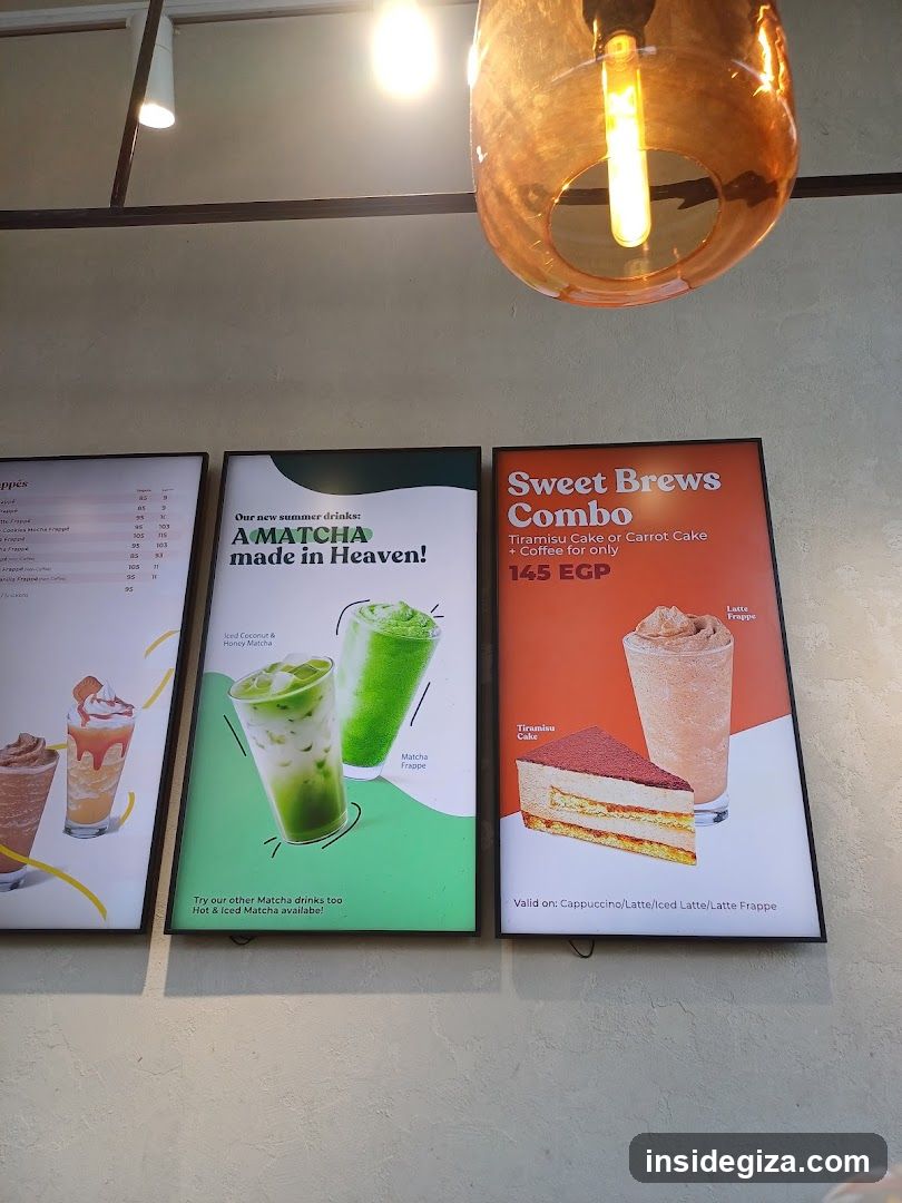Three framed posters mounted on a textured wall inside a cafe or coffee shop. The left poster shows two iced drinks with prices listed in Arabic script. The center poster advertises 'A MATCHA made in Heaven!' featuring Matcha Frappe and Iced Coconut & Honey Matcha. The right poster promotes the 'Sweet Brews Combo' (Tiramisu Cake or Carrot Cake + Coffee) for 145 EGP, valid on Cappuccino/Latte/Iced Latte/Latte Frappe.