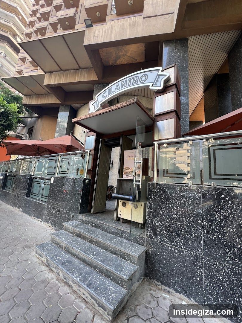 Exterior view of Cilantro restaurant entrance with visible signage above the door, glass doors, and marble steps leading up to the storefront.