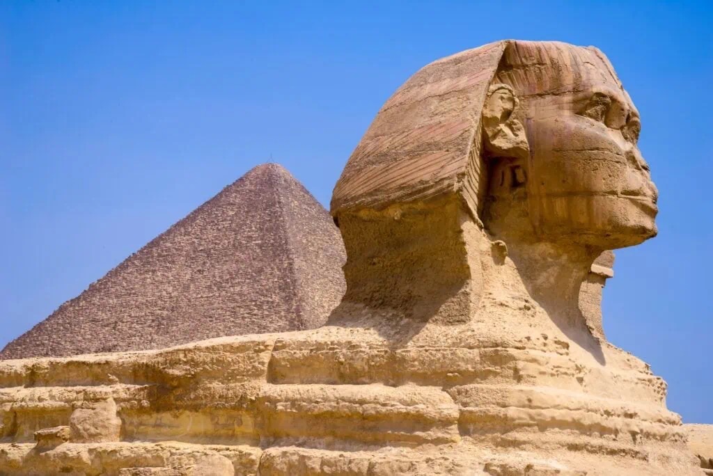 The Great Sphinx carved from limestone with the Giza pyramids in the background